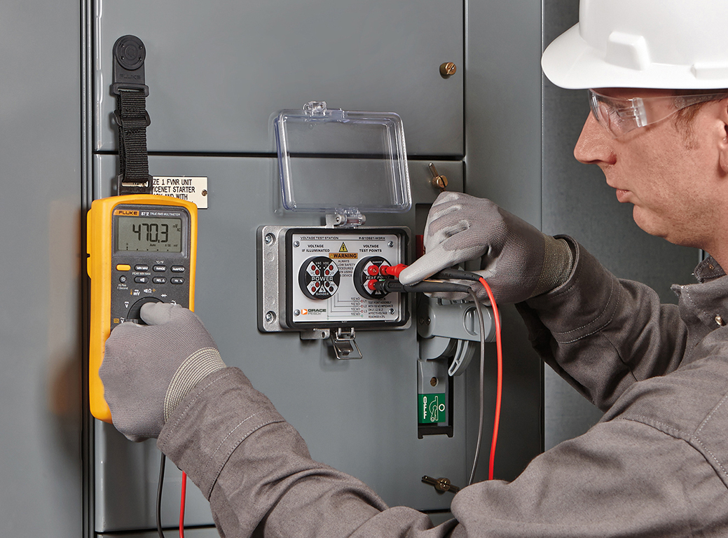 A worker tests voltage with the door closed. Image by Grace Technologies,