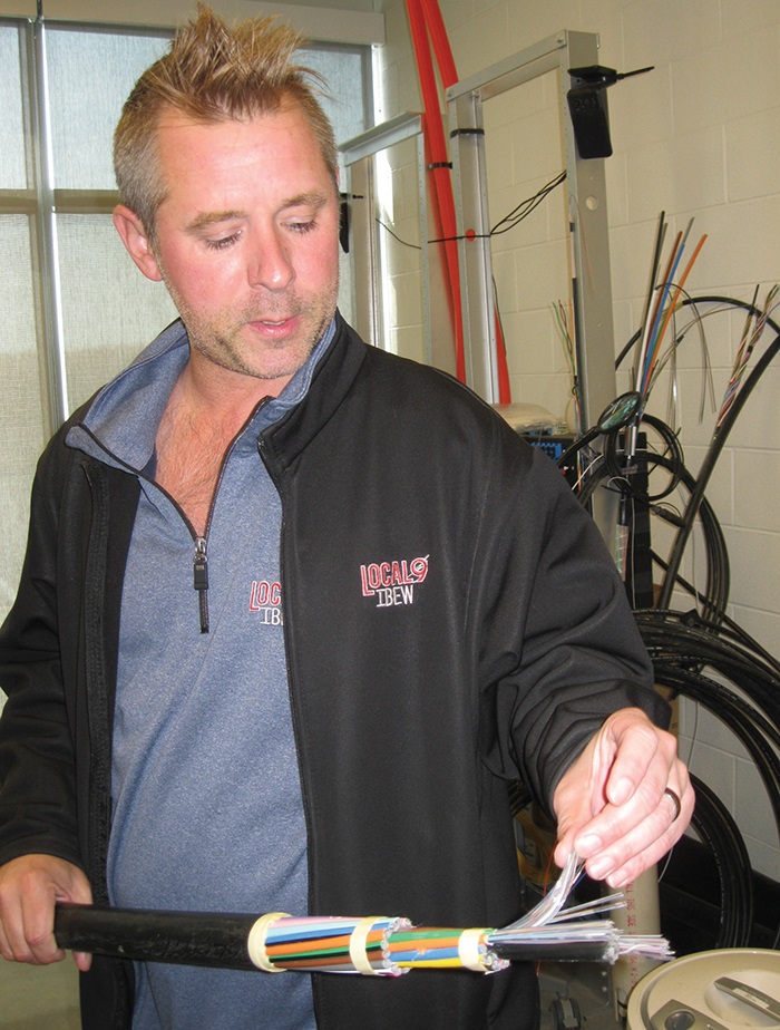 A man holds multiple wires. Image by Susan DeGrane.