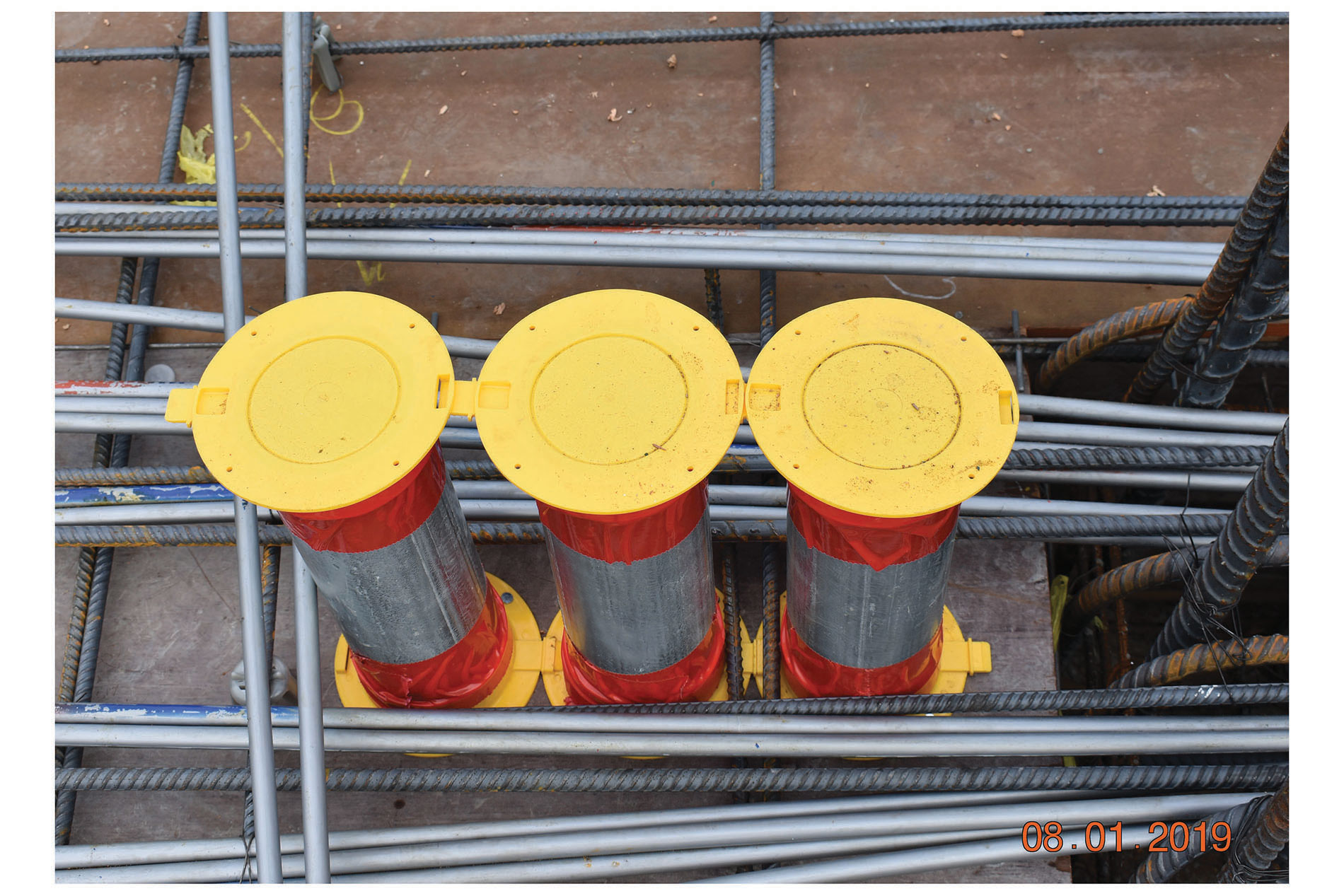 0822_ISC_Arlington Conjoined yellow conduit caps on three metal cylinders. Image by Arlington Industries.
