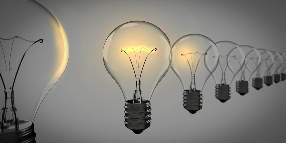 Leadership represented by a glowing light bulb among a line of unlit bulbs.