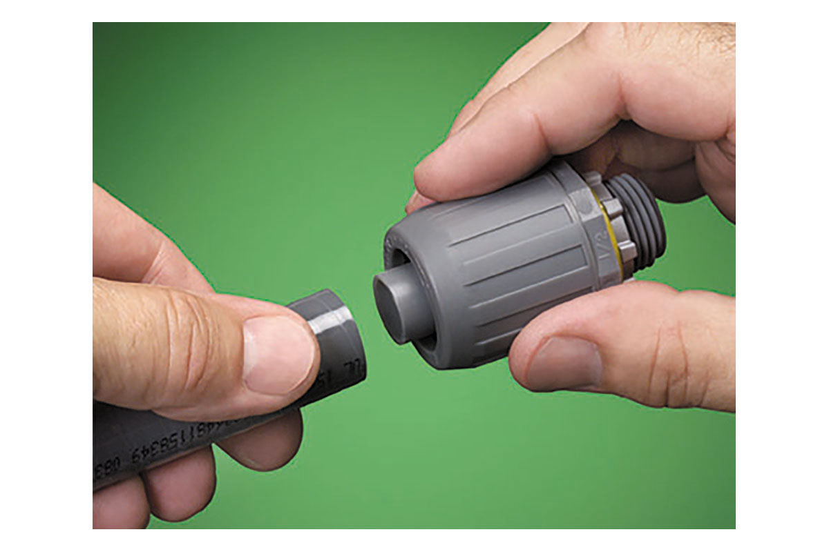Hands holding a gray push-on connector against a green background. Image by Arlington Industries.