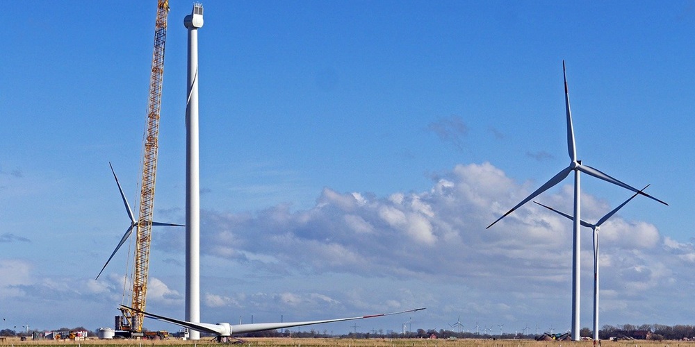 A wind turbine (left) under construction, with two completed wind turbines in the background