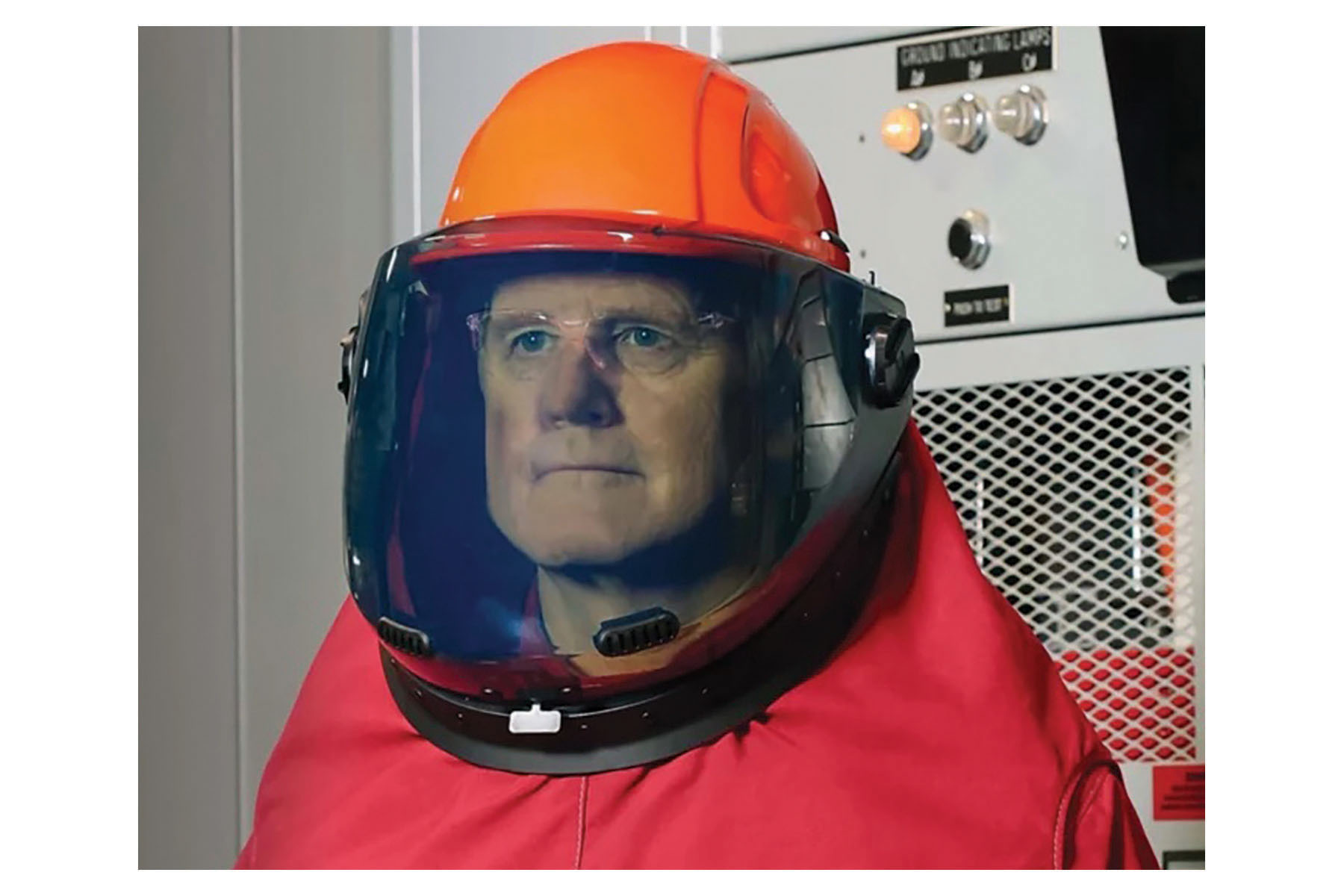A man in a red suit with an orange hard hat and gray face shield. Image by Honeywell.