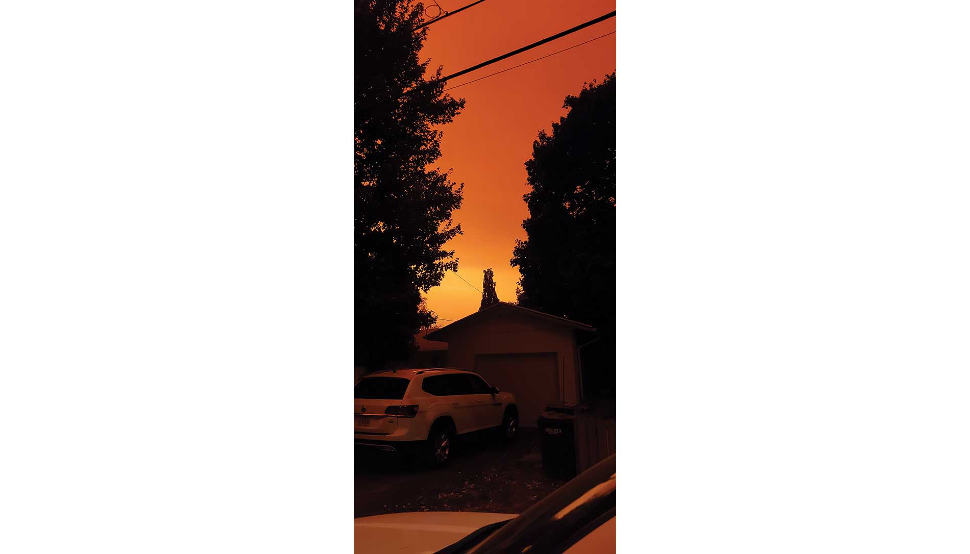 Orange smoke fills the sky over a house and cars. Image by Mark Hopkins, Cherry City Electric.