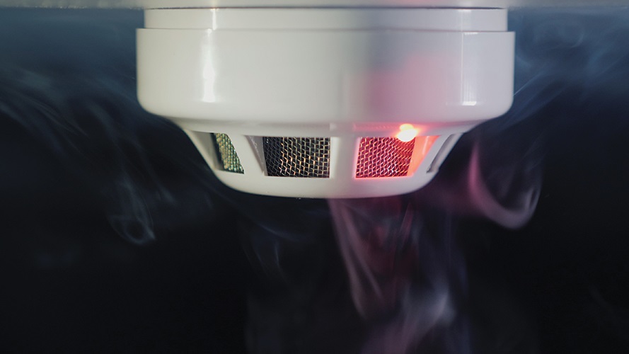 Smoke detector with a red light on surrounded by smoke