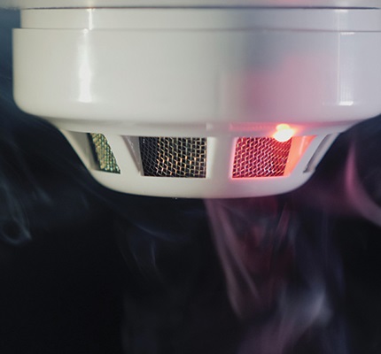 Smoke detector with a red light on surrounded by smoke