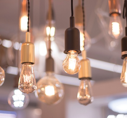Various lightbulbs, turned on, hang from a ceiling