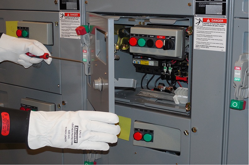 Two gloved hands work on a motor disconnect panel