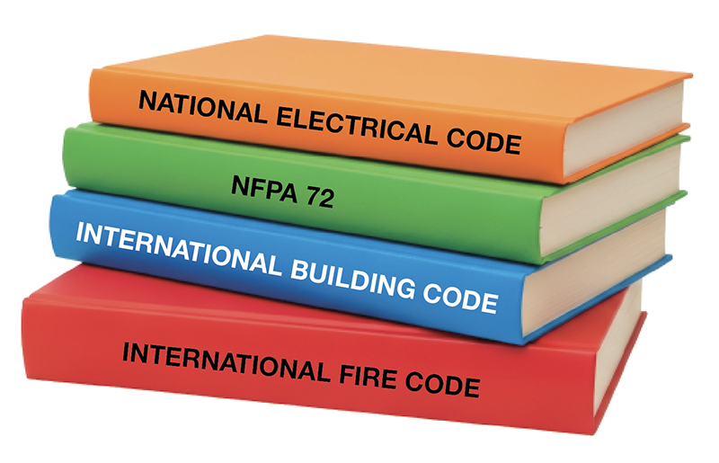 A stack of books labeled with various code names: National Electrical Code, NFPA 72, International Building Code and International Fire Code