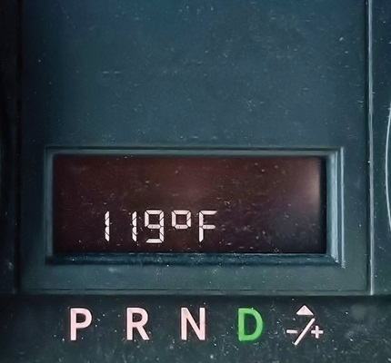 A car's dashboard shows the outside temperature at 119 degrees Fahrenheit. At least it’s a dry heat.