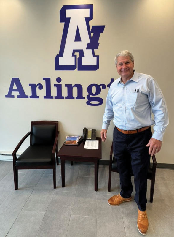 David Long, CEO of NECA, stands in front of the Arlington Industries logo at Arlington Industries' headquarters