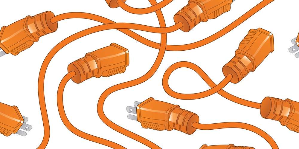 Orange electrical cords with plugs overlaying each other | iStock / Filo