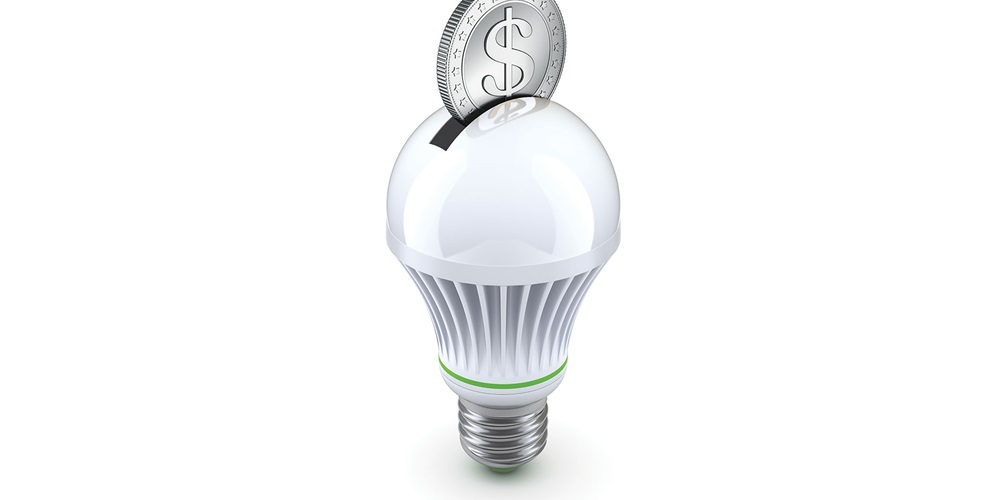 Lightbulb with a slot in it like a piggybank with a coin resting in the slot.