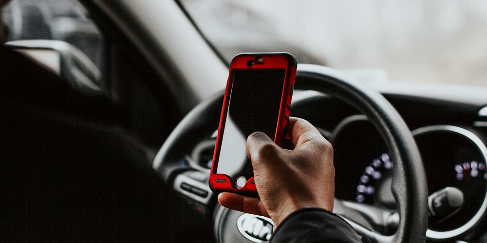 Person driving with cell phone in hand