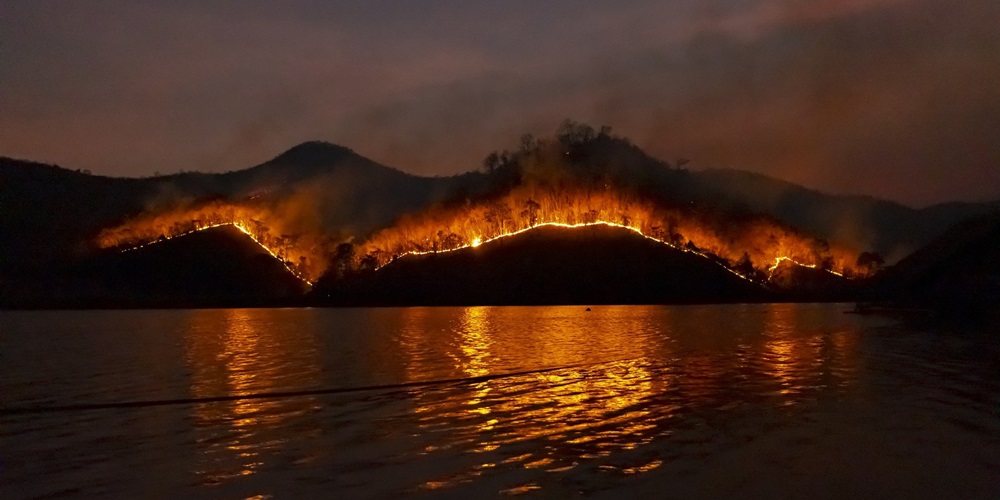 A wildfire burns through hills at night