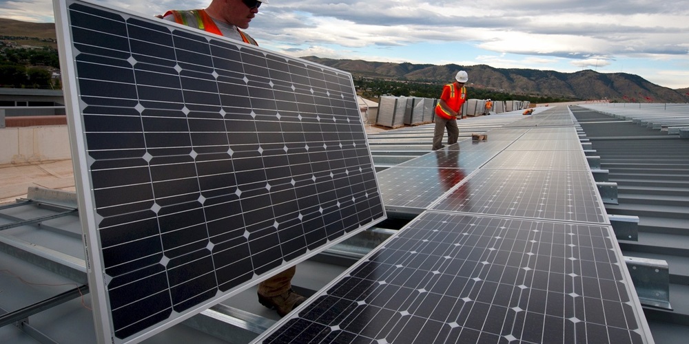 Two contractors installing solar panels on a roof