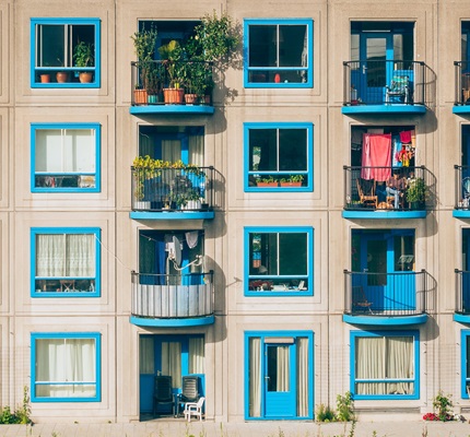 Tan apartment face with blue balconies. Image by Ján Jakub Naništa / Unsplash.