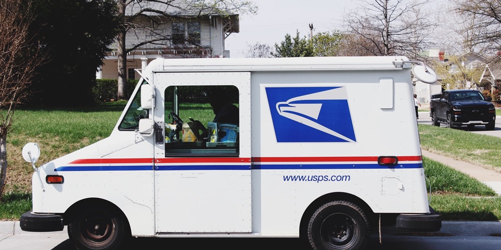A USPS delivery truck outside of a residence | Unsplash / Pope Moysuh