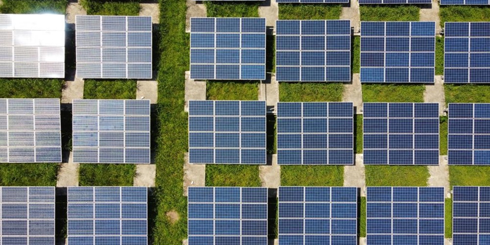 Solar panels over grass. Image by Anders J / Unsplash.
