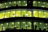 Office building at night with illuminated workspaces, illustrating lighting energy usage patterns relevant to bilevel switching and occupancy sensor strategies.