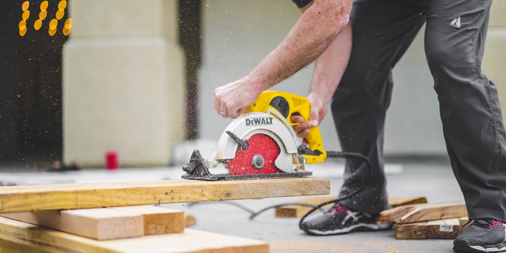 A person cutting a piece of lumber with a circular saw | Photo by Greyson Joralemon on Unsplash