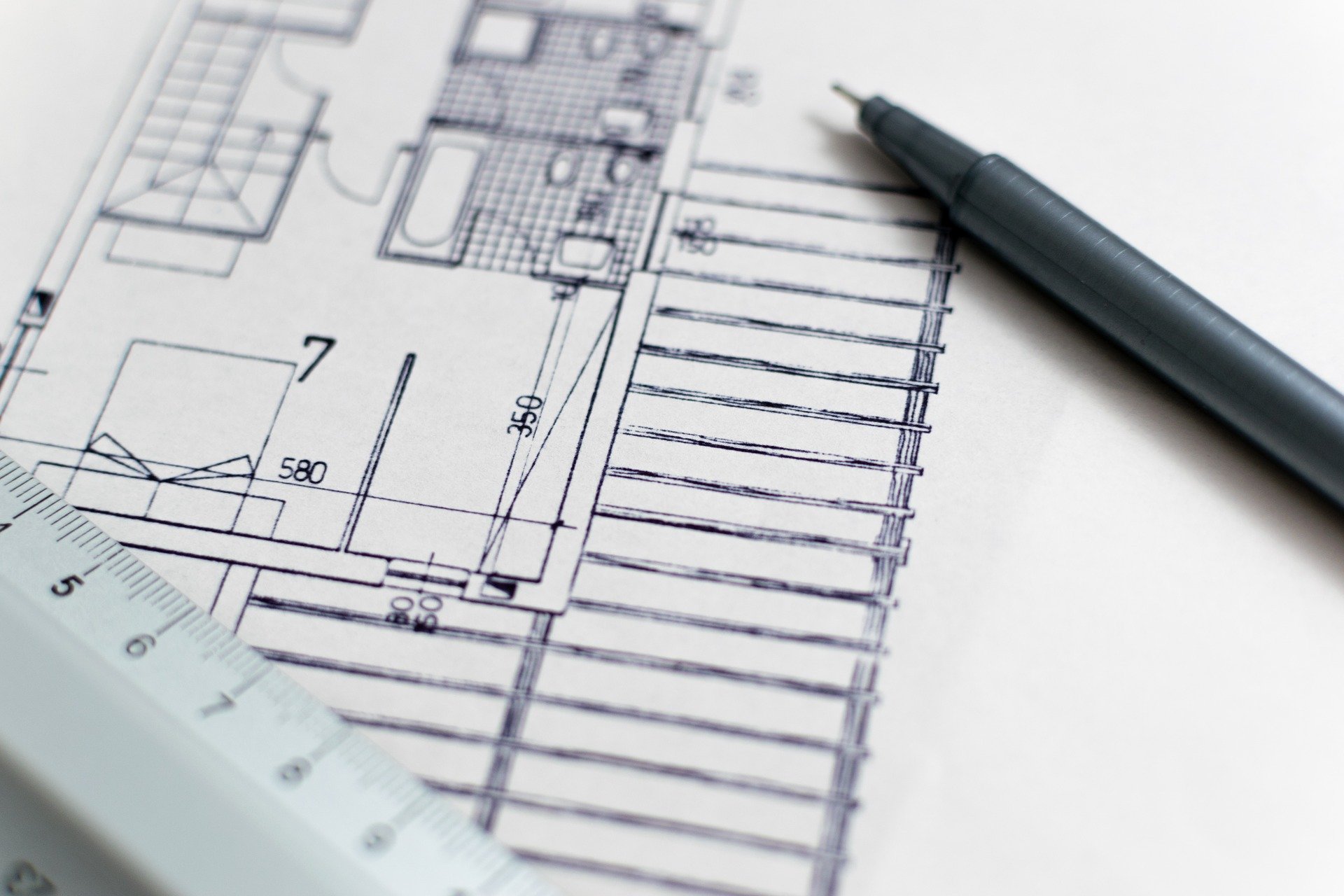 architecture-1857175_1920.jpg A black & white construction blueprint with a pen and rule laying on top of the paper