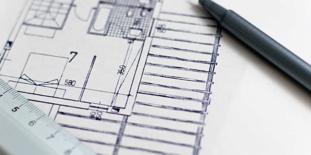 A black & white construction blueprint with a pen and rule laying on top of the paper