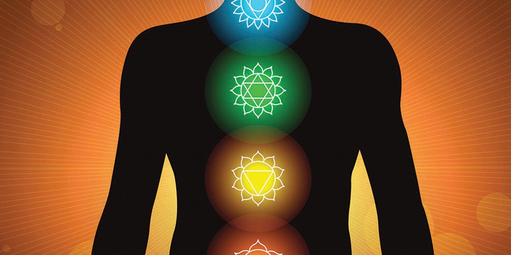 A silhouette of a human body overlaid with symbols for the 7 chakras | Getty Images / Shoo_Arts