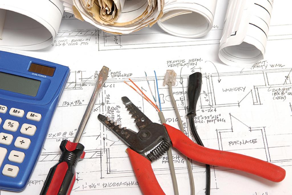 Wire cutters, cords, a screwdriver and a calculator on top of a blueprint. Image by iStock.