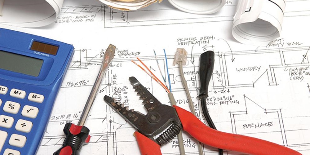 Wire cutters, cords, a screwdriver and a calculator on top of a blueprint. Image by iStock.