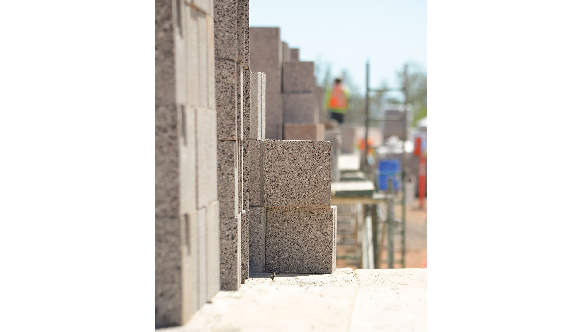Stacked cinderblocks. A construction worker and ladder are in the background. Image by The Weitz Co.