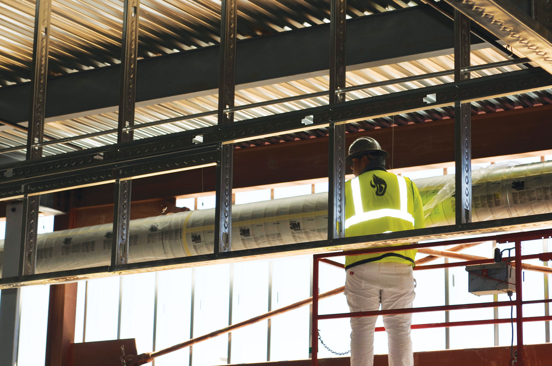A construction worker stands in a sunny, partially-constructed building. Image by The Weitz Co.