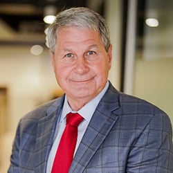 A man, David Long, smiles in front of an out-of-focus office space.