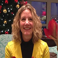 Deborah-OMara-headshot-edited A woman, Deborah O'Mara, smiles in front of a Christmas tree.