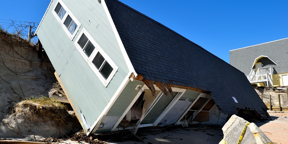 A displaced home leaning on its front side after a hurricane.