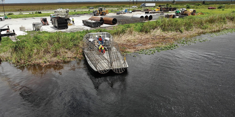 A small barge carrying wire columns sits between a canal and grass. Image by Aldridge Electric.