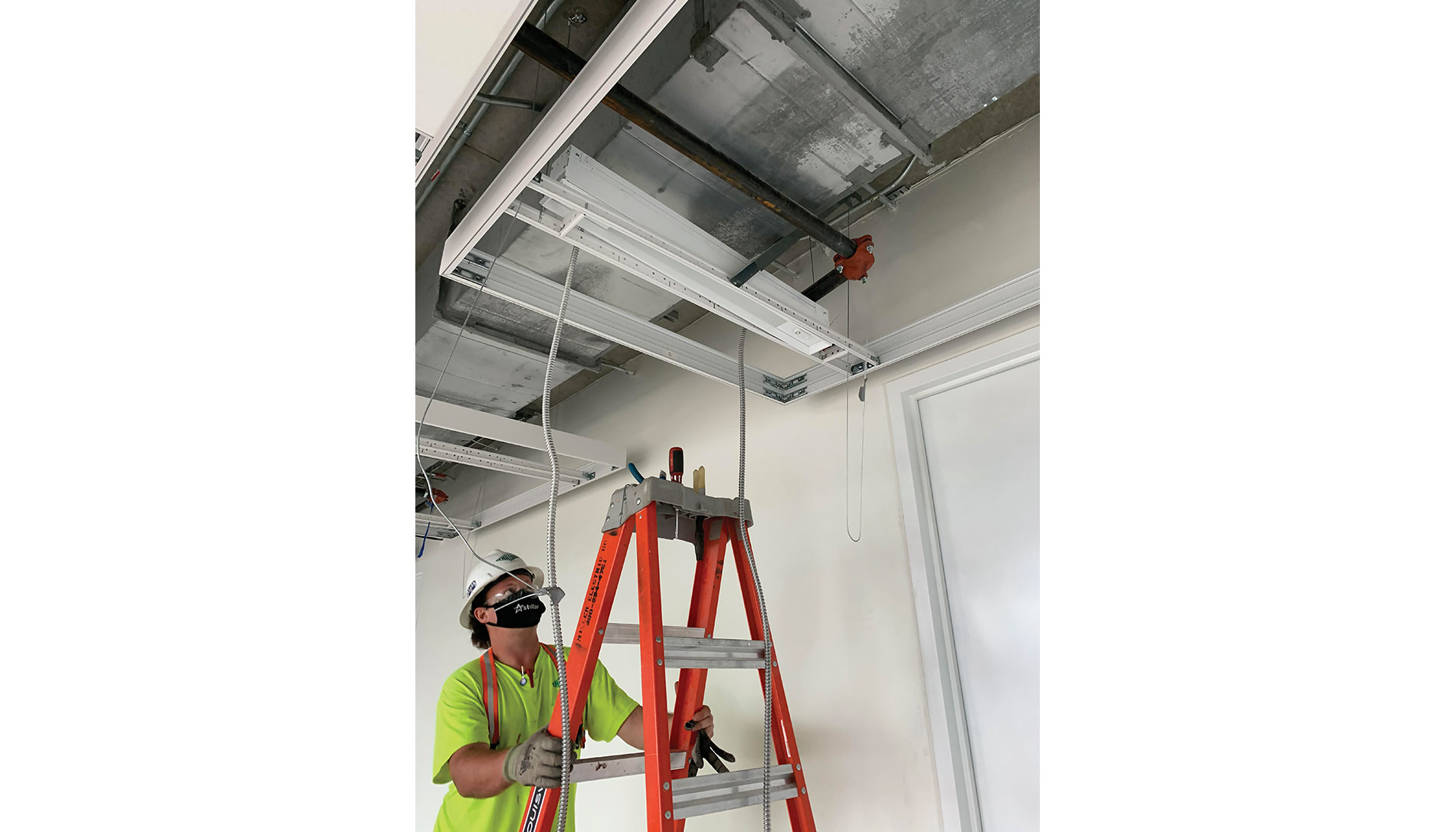 A worker climbs a ladder towards a light. Image by Miller Electric.