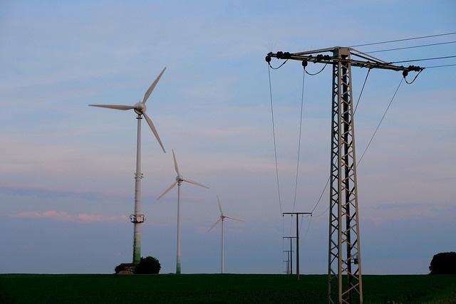 wind mills next to a high-voltage transmission line. Image by Holger Schué from Pixabay