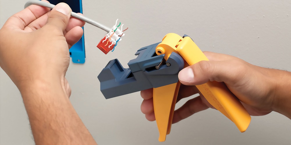 Hands hold a gray and yellow JackRapid punchdown tool. Image by www.flukenetworks.com.