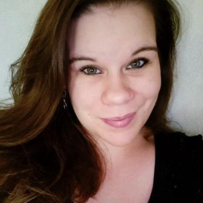 A woman with brown hair and a black shirt smiles at the camera