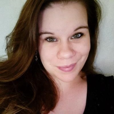A woman with brown hair and a black shirt smiles at the camera