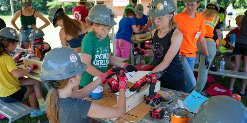Girls in hard hats and gloves work at picnic tables. Photos courtesy of Minneapolis Chapter of NECA.