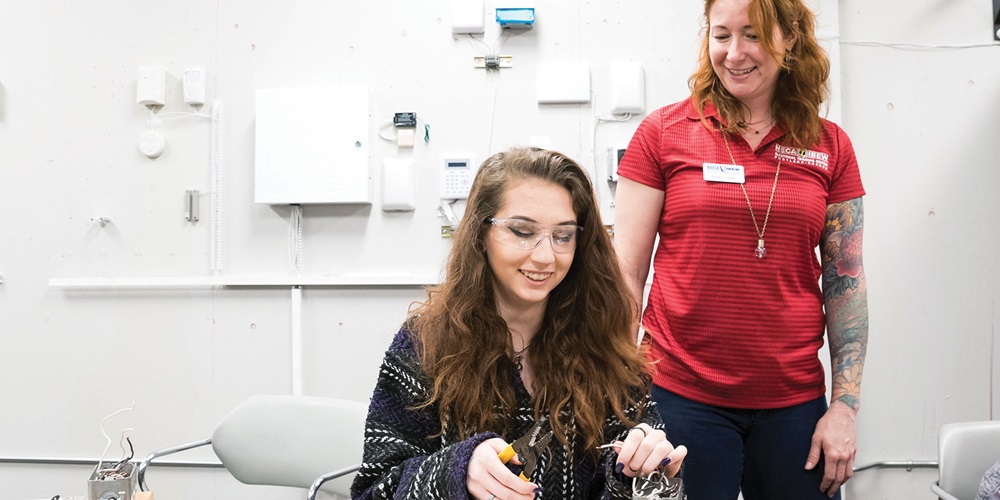 Bridget Quinn instructs students on wiring a light and switch at Oregon Tradeswomen's annual career fair