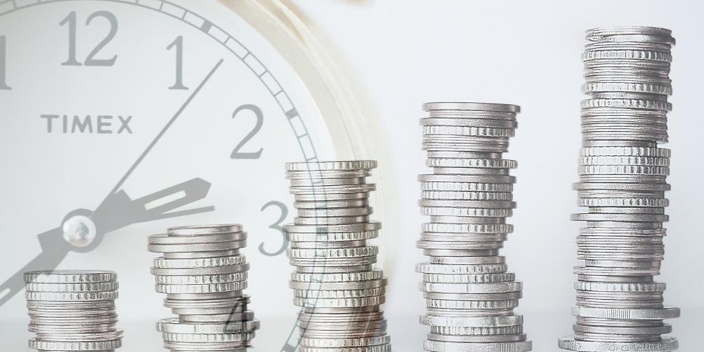 Silver coins overlaid with a translucent clock. Image by Shutterstock.