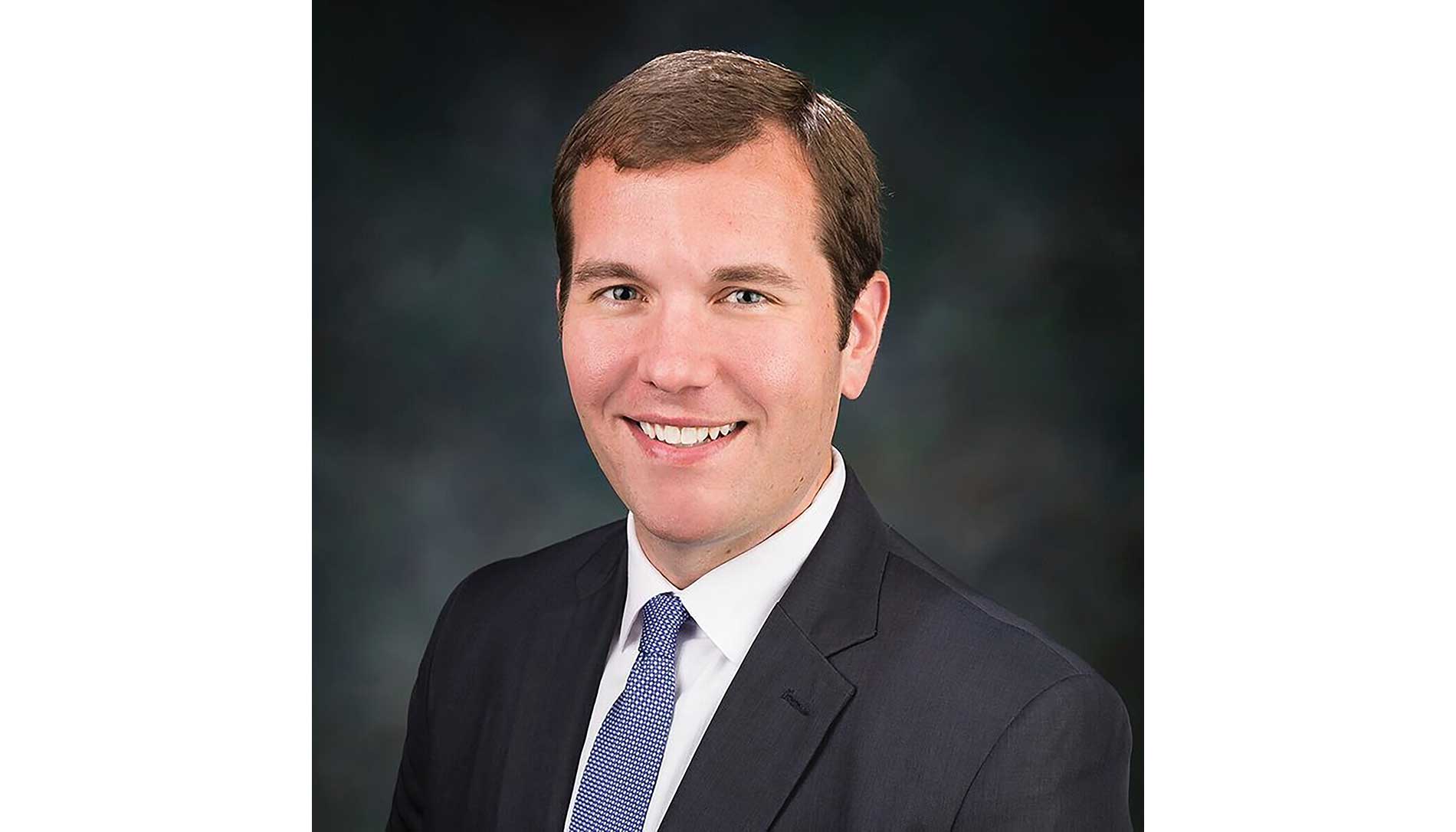 A photo of a man, Andrew Brisbo, against a gray background.