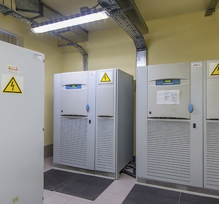 Three uninterruptible power supply (UPS) systems, labeled with an electrical hazard warning sticker