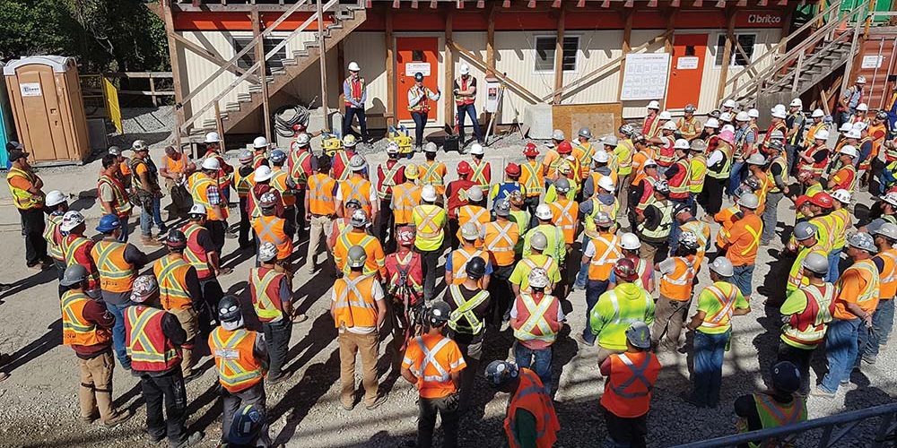 Workers stand in a lot outside a building. Image by Western Pacific Enterprises Ltd.