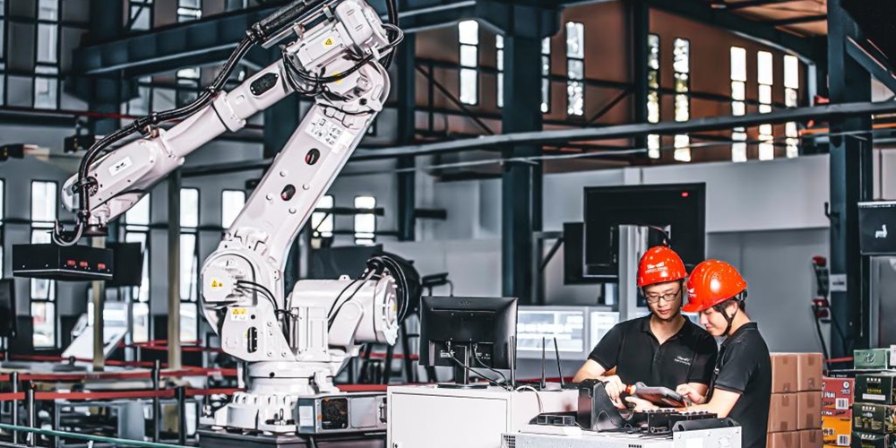 Workers ina  lab by a small crane robot. Image by Unsplash / Mech Mind.