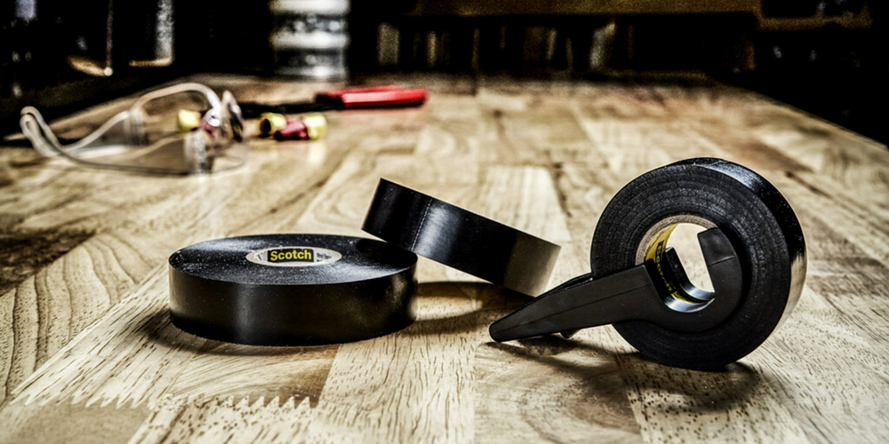 Three rolls of black Scotch tape on a wooden surface. Image by 3M.