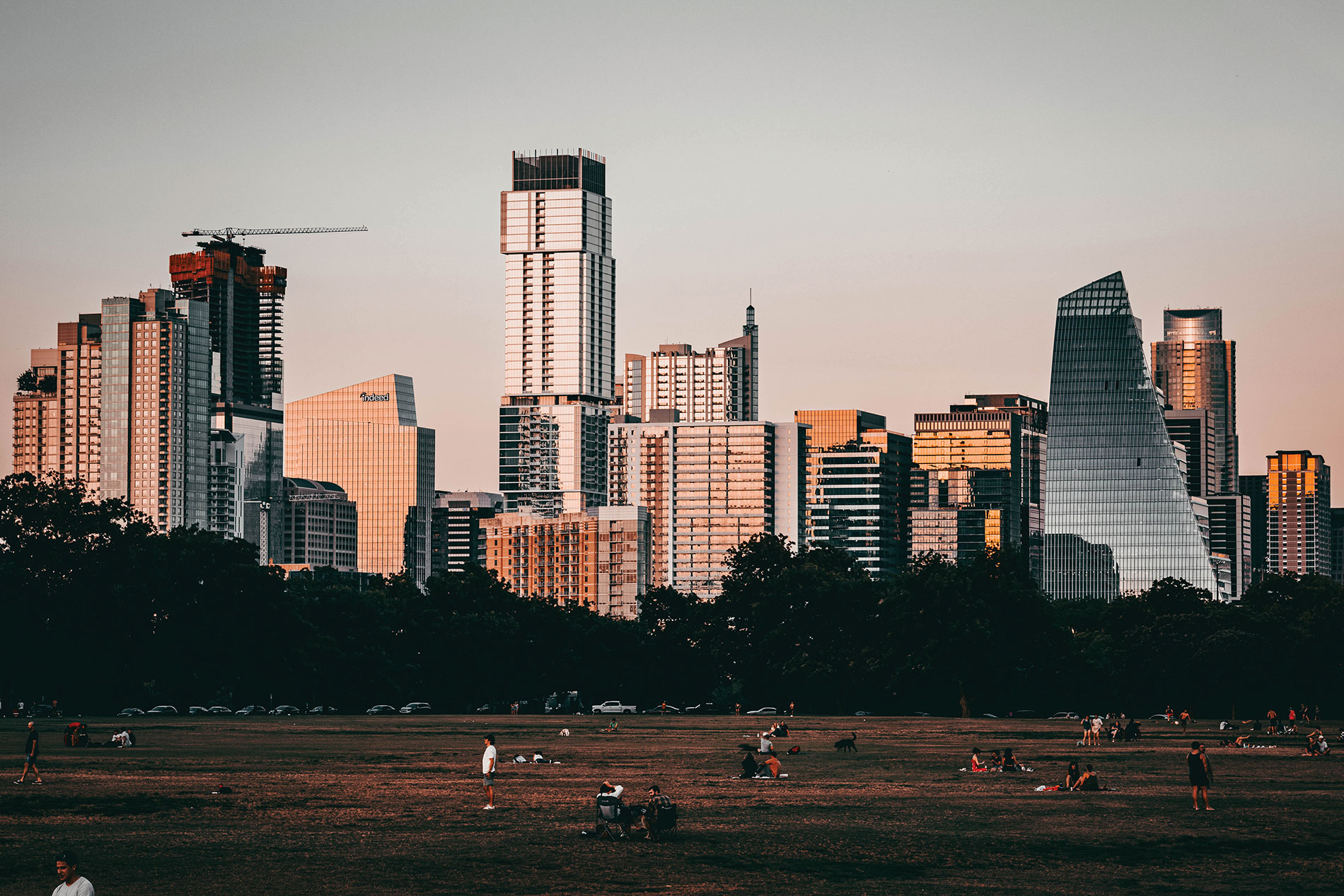 People in a park against the Austin skyline at dusk. Image by Parker George / PFG.